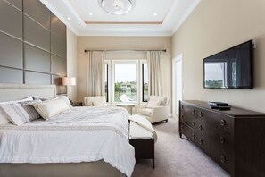 Une chambre à coucher avec un grand lit, une commode, un téléviseur et une fenêtre avec des rideaux.