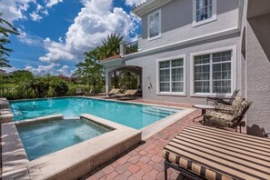 Un espace piscine comprenant un jacuzzi, des chaises longues et une table de patio.