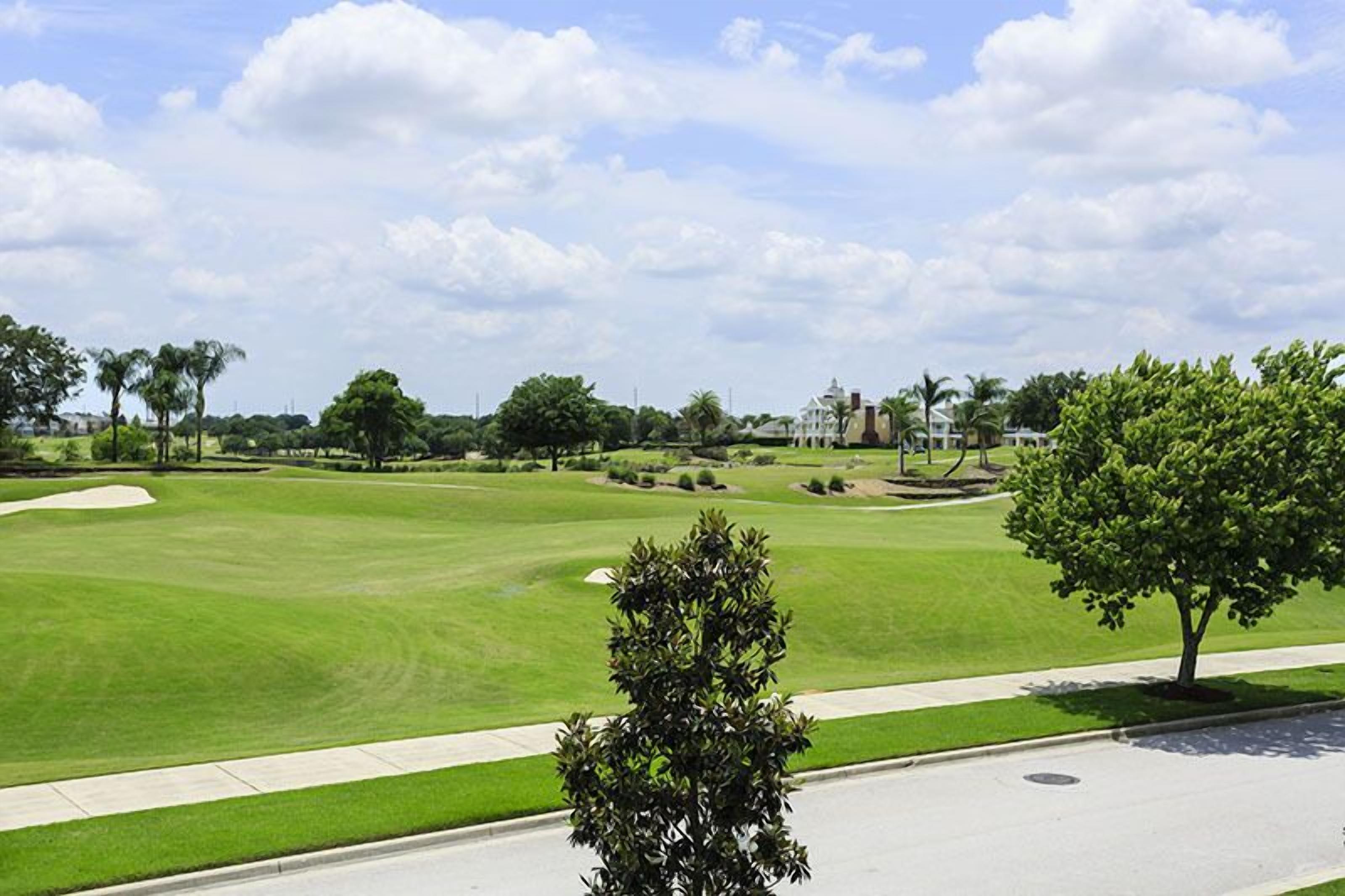 A golf course with a well-maintained lawn, sand bunkers, and a clear sky.