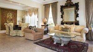 Un salón amplio con un sofá beige, una mesa de centro redonda de cristal y una alfombra estampada.