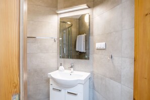 A modern bathroom with a white sink, mirror, and shower.