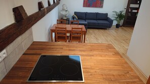 Cozy kitchen with induction cooktop, dining table, and sofa, perfect for casual meals and relaxation.