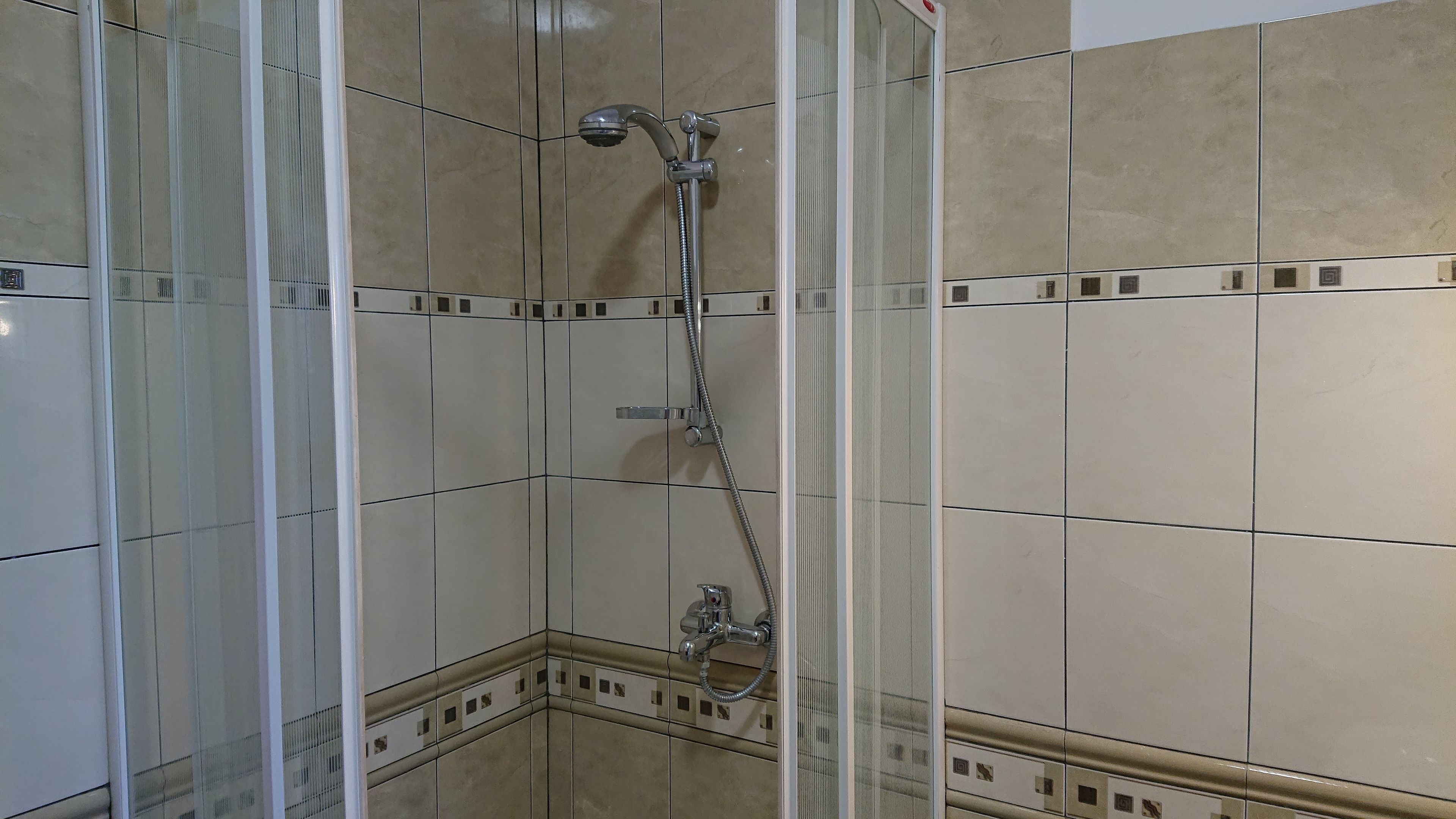 A shower with a handheld showerhead and a wall-mounted faucet.