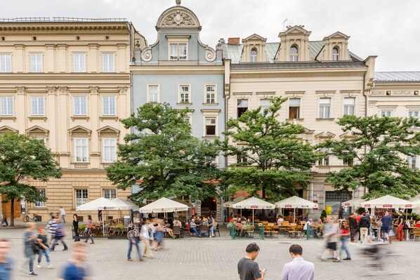 A public square with historic buildings, outdoor cafes, and pedestrians.