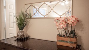 Ein Holzkonsolentisch mit einer dekorativen Vase und einem Holzpflanzgefäß mit rosafarbenen Orchideen.