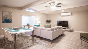 Ein modernes Wohnzimmer mit Essbereich, Deckenventilator, Klimaanlage und Flachbildfernseher.