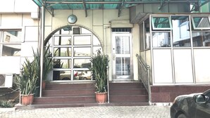 A building entrance with a covered entrance, a staircase, and potted plants. - Sun On Hotel (Lagos)