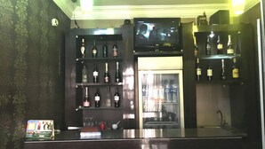 A bar area with shelves of liquor bottles, a television mounted above the bar, and a counter with a menu. - Sun On Hotel (Lagos)