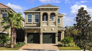 A two-story house with a front porch, a garage, and a well-maintained lawn. - Je58253 - Reunion Resort - 6 Bed 5 Baths Villa (Kissimmee)