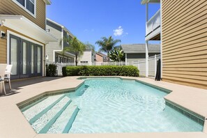 A swimming pool surrounded by apartment buildings with balconies, a white fence, and a clear blue sky. - Je58869 - Reunion Resort - 5 Bed 4 Baths Villa (Kissimmee)