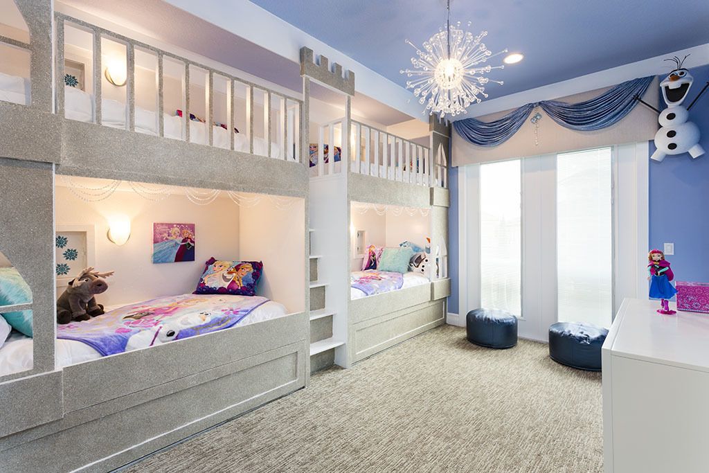 Un dormitorio infantil con literas, una zona de juegos y un ventanal grande.