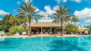 A hotel with a swimming pool, palm trees, and a covered outdoor area with seating. - Je58859 - Reunion Resort - 8 Bed 8 Baths Villa (Kissimmee)