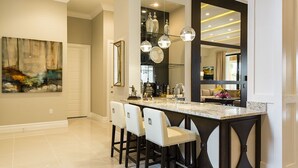 A modern kitchen with a bar area, featuring a large island with stools, pendant lighting, and a large mirror. - Je58859 - Reunion Resort - 8 Bed 8 Baths Villa (Kissimmee)