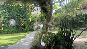 A garden pathway with a statue of an elephant, surrounded by lush greenery and various plants. - Graha Madesimon (Batubulan)