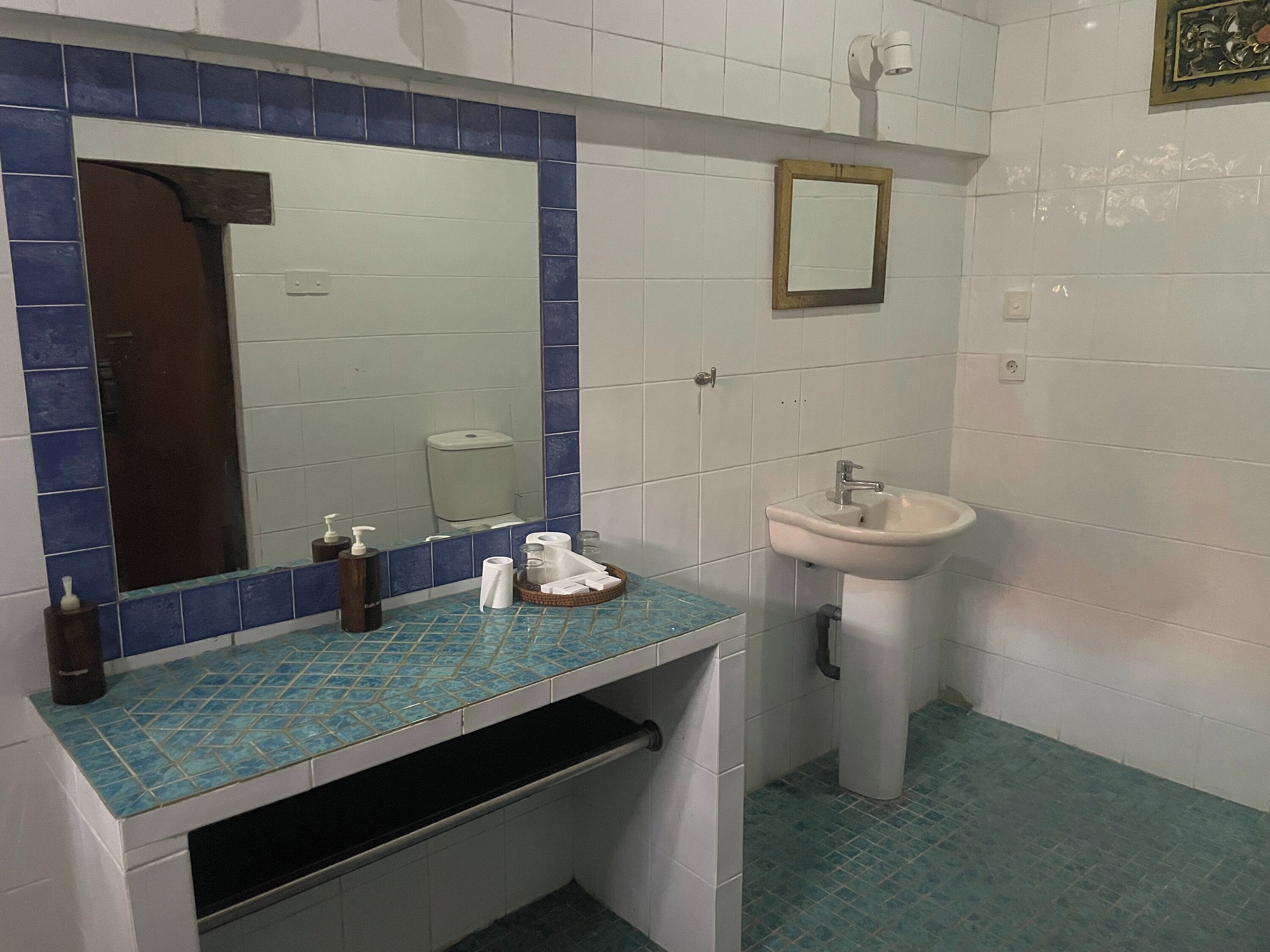 A bathroom with a sink, mirror, and blue-tiled countertop.