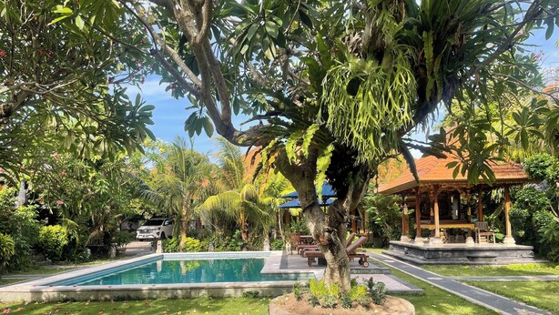 A pool surrounded by lush greenery, a gazebo, and a well-maintained lawn. - Graha Madesimon (Batubulan)