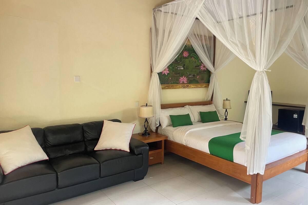 Quarto com cama de dossel, sofá e mesa de cabeceira com abajures.