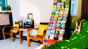 Ein Zimmer mit einem Holztisch, Stühlen, einem kleinen Fernseher und einer Wand voller Reisebroschüren.