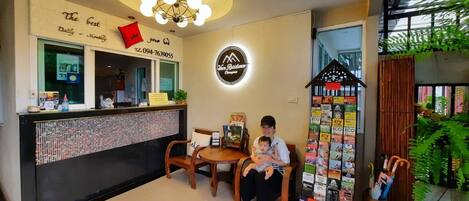 A reception area with a counter, a neon sign, a small table with chairs, and a wall with various items.