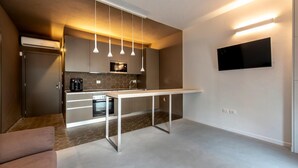 A modern kitchen with a central island, pendant lights, a flat-screen TV, and a built-in oven. - Casa Ercoli (Vinci)