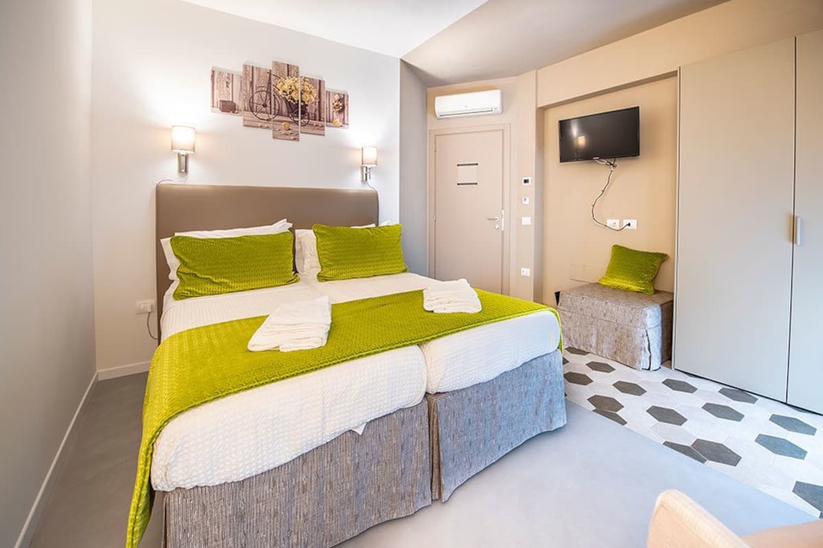 A modern bedroom with a bed, a television, and a small stool.