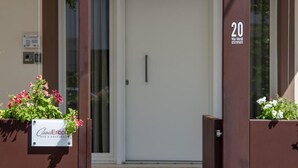 A modern building entrance with a glass door, a brown metal gate, and a sign indicating room number 20. - Casa Ercoli (Vinci)