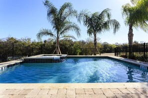 A swimming pool with a waterfall feature, surrounded by palm trees and a black metal fence. - Je59694 - Reunion Resort - 5 Bed 5 Baths Villa (Kissimmee)