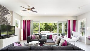 A modern living room with a sectional sofa, a flat-screen TV, and a ceiling fan.