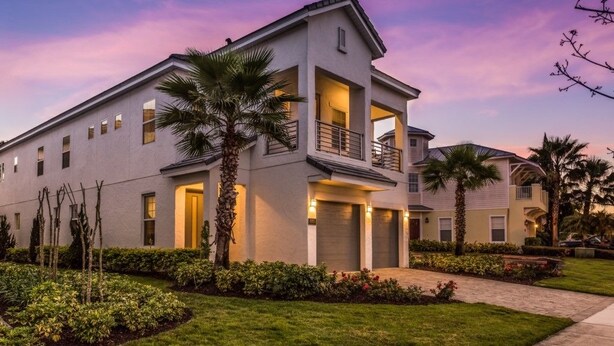 A modern two-story building with a balcony, a driveway, and well-maintained landscaping.