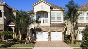 A two-story house with a central entrance, a balcony, and a garage with two doors. - Je61079 - Reunion Resort - 5 Bed 4 Baths Villa (Kissimmee)