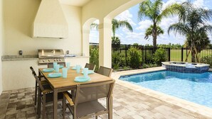 An outdoor patio with a pool, a barbecue grill, and a dining table set for four. - Je61079 - Reunion Resort - 5 Bed 4 Baths Villa (Kissimmee)