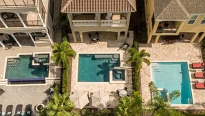 Zona de piscina en la azotea con dos piscinas, sillas de descanso y palmeras.