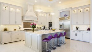A modern kitchen with white cabinetry, a central island with bar stools, stainless steel appliances, and pendant lighting. - Je61091 - Reunion Resort - 7 Bed 7 Baths Villa (Kissimmee)