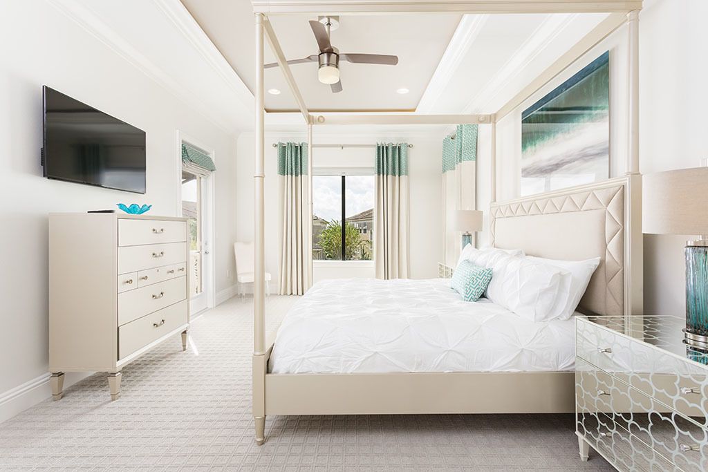 A bedroom with a bed, a dresser, a TV, and a ceiling fan.