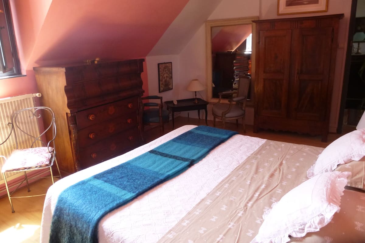 A bedroom with a bed, a dresser, a chair, a desk, and a wardrobe.