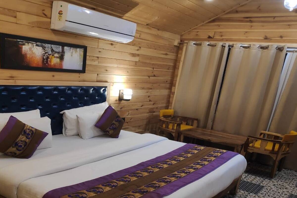 A wooden room with a bed, a table, and chairs.