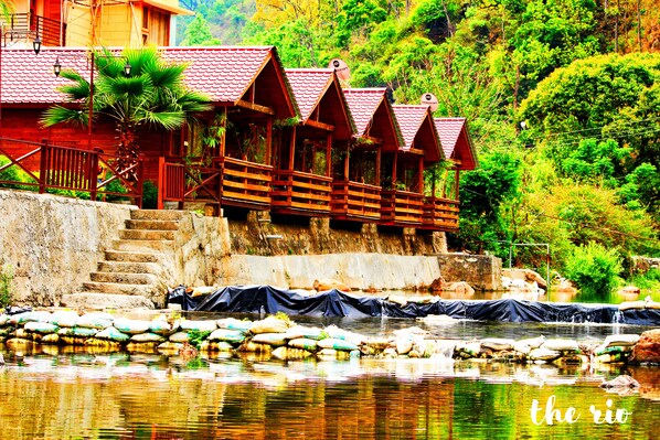 A wooden structure with red roofs and a stone staircase leading down to a river. - Rio Resort (Lansdowne)