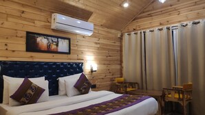 A wooden-paneled room with a bed, a mounted air conditioner, a painting, and a window with curtains. - Rio Resort (Lansdowne)
