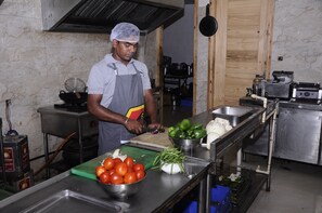 A kitchen with stainless steel appliances, a cutting board with vegetables, and a person preparing food.