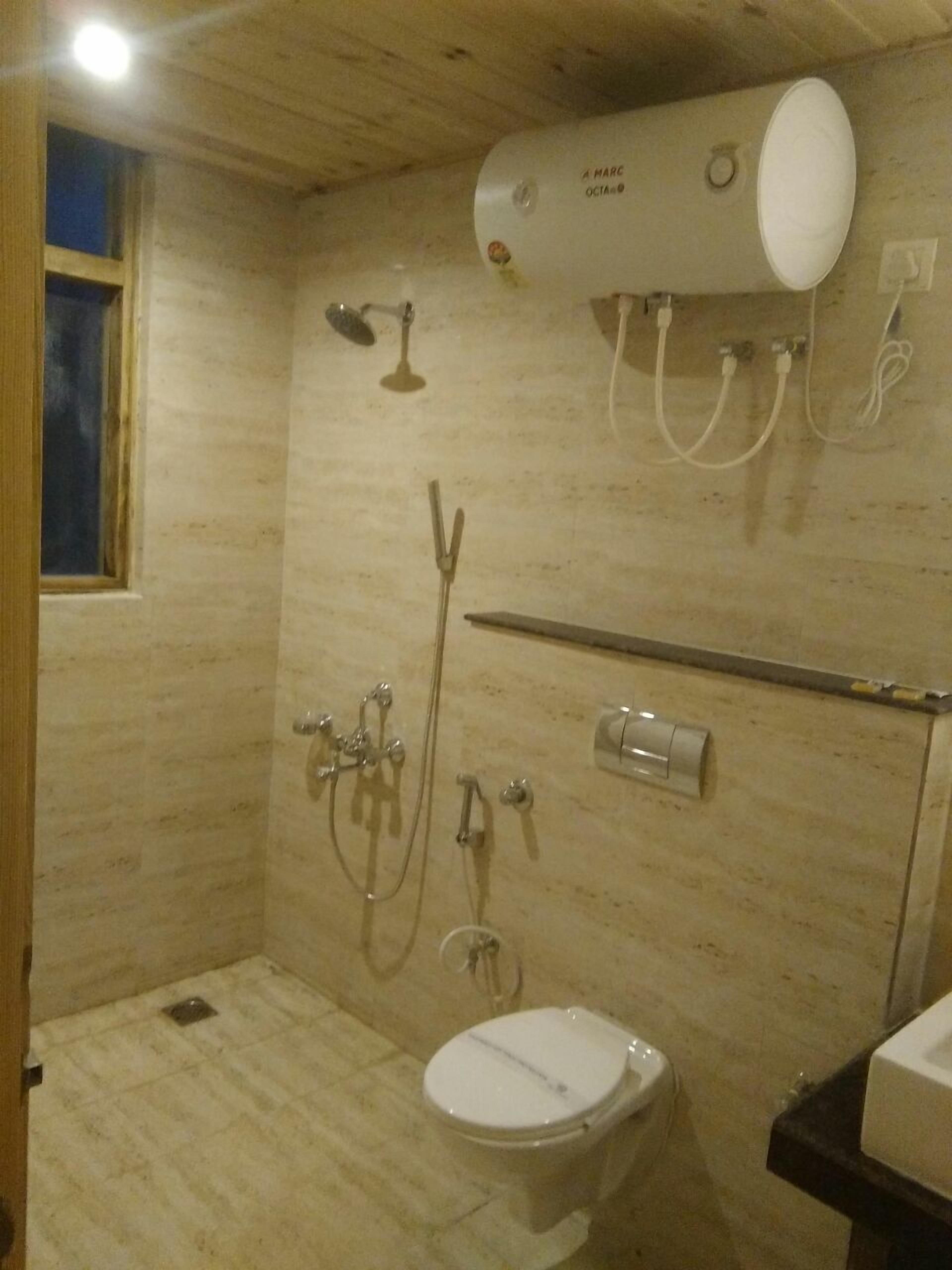A small, compact bathroom with a toilet, a shower, and a sink.