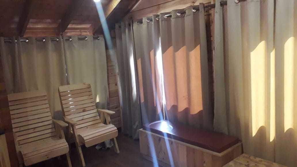 A room with wooden furniture, including a bench and chairs, and a window with curtains.