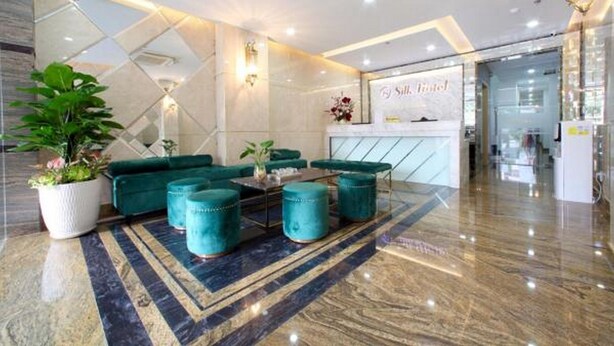 A modern lobby with a reception desk, green sofas, and a marble floor. - RedDoorz Plus near Tan Son Nhat Airport 2 (Ho Chi Minh City)