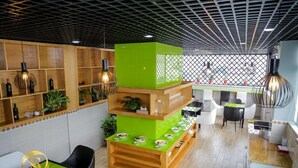 A restaurant area with wooden shelves, hanging lights, and a green counter with dishes. - RedDoorz Plus near Tan Son Nhat Airport 2 (Ho Chi Minh City)