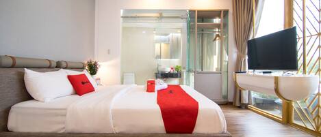 A modern hotel room with a large bed, a desk, and a TV.