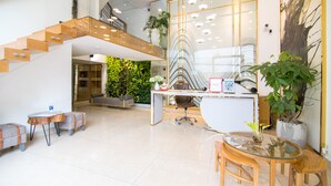 A spacious lobby with a staircase, a reception desk, and a seating area. - RedDoorz Plus near Saigon Train Station (Ho Chi Minh City)
