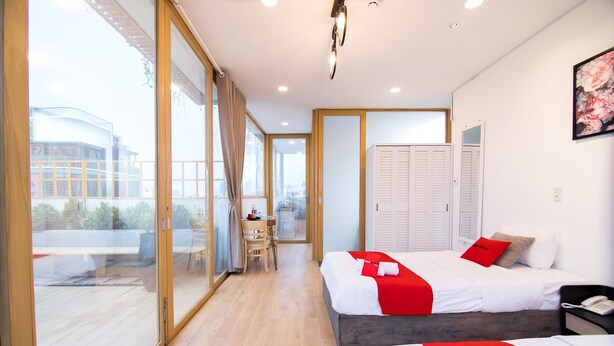 A modern hotel room with two beds, a dining area, and a view of the city. - RedDoorz Plus near Saigon Train Station (Ho Chi Minh City)