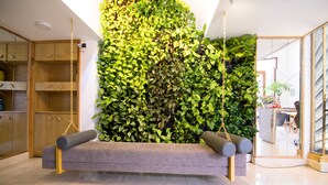A modern interior with a grey sofa, wooden shelving, and a green vertical garden wall. - RedDoorz Plus near Saigon Train Station (Ho Chi Minh City)