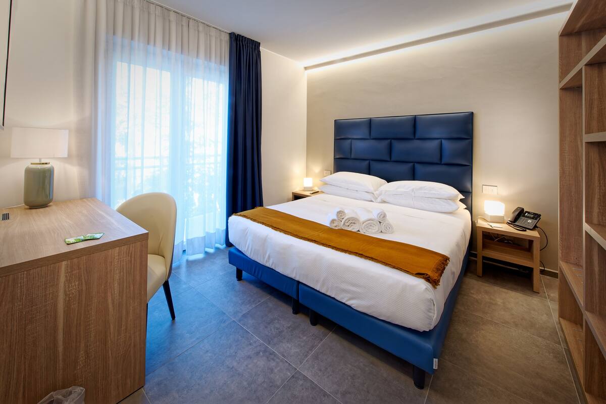 Et hotelværelse med seng, sengeborde, skrivebord og stol.