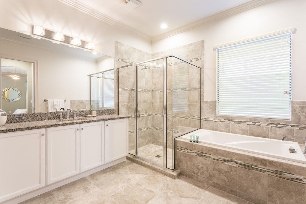 Une salle de bain moderne avec une douche à parois de verre, une grande baignoire et un meuble-lavabo avec un miroir.