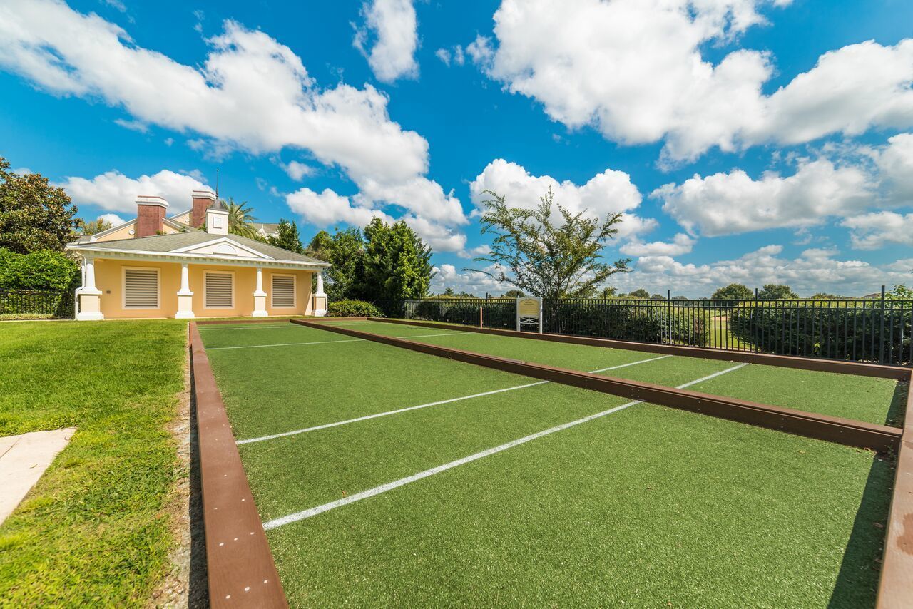 Une maison avec une pelouse verdoyante et un court de tennis.